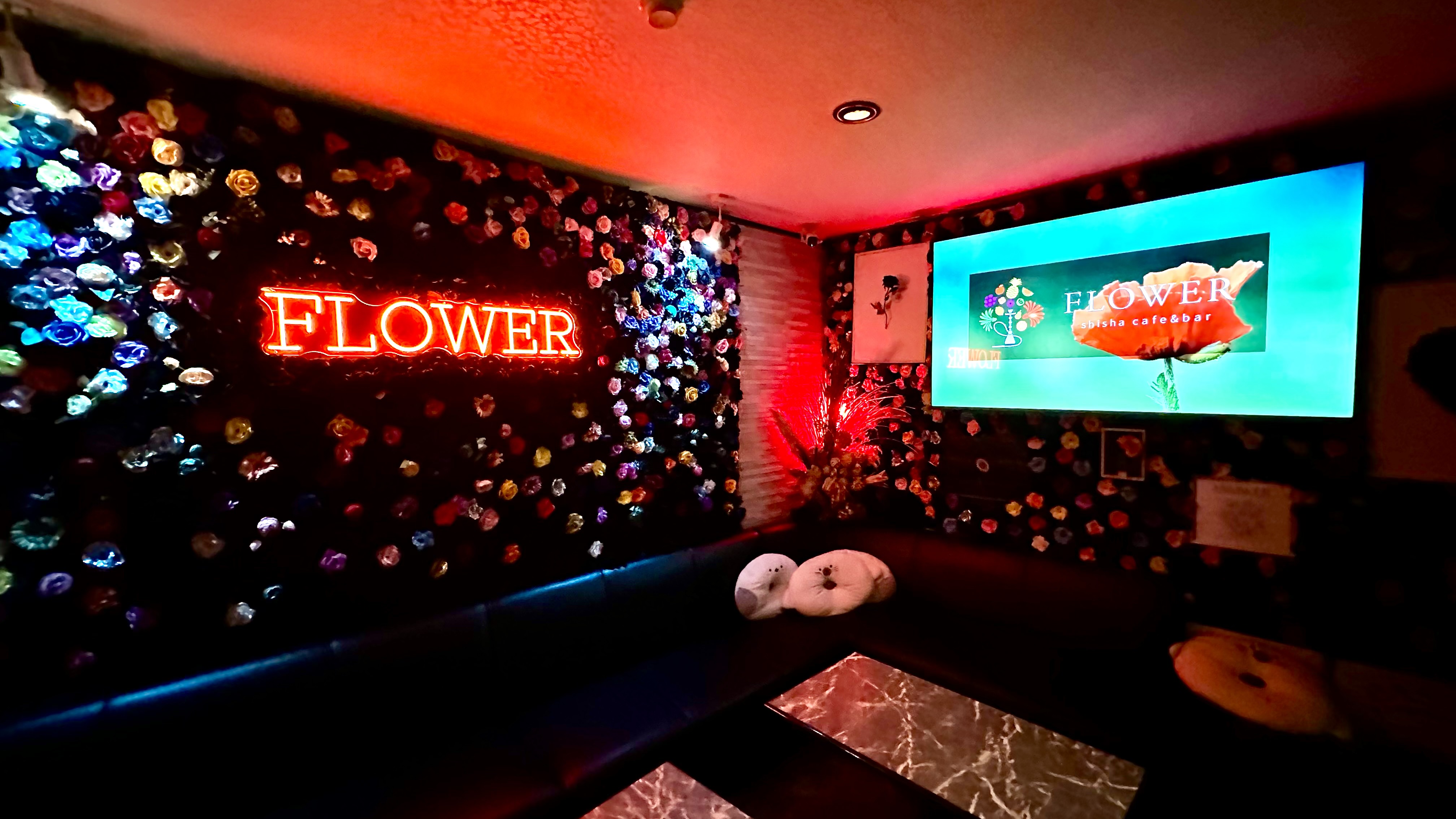 無数の造花で覆われた壁とソファ席が落ち着いた照明に照らされたFLOWERの店内